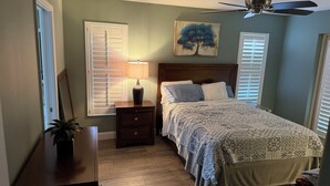 Un dormitorio con cama, mesita de noche, lámpara y ventilador de techo.
