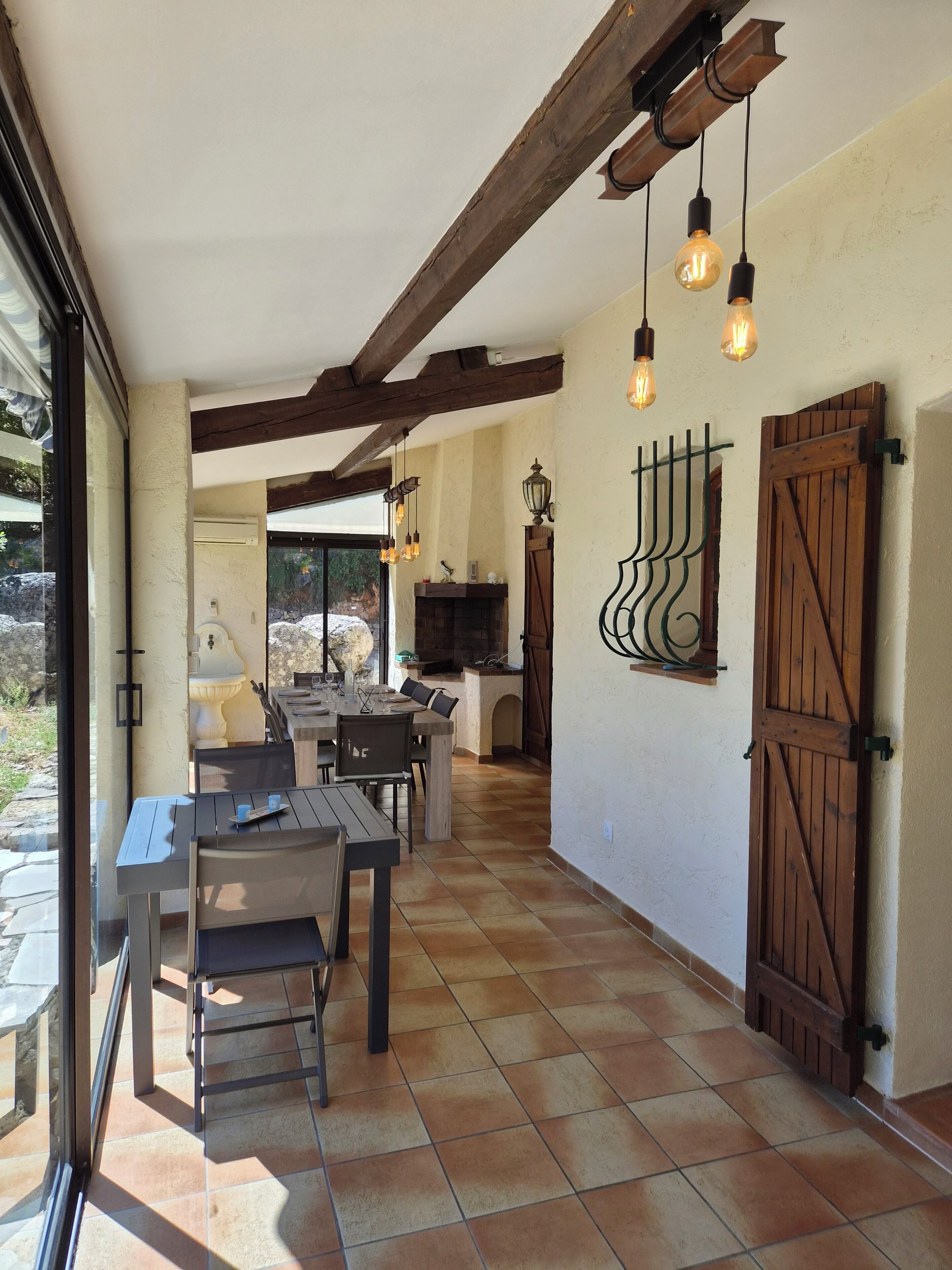 A dining area with a table and chairs, a fireplace, and a view through a glass door.