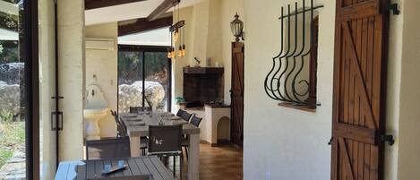 A dining area with a table and chairs, a fireplace, and a view through a glass door.
