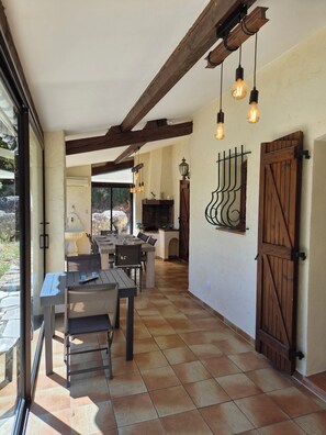 A dining area with a table and chairs, a fireplace, and a view through a glass door. - Villa The Sylamston - The Waterfall Experience (Sillans-la-Cascade)