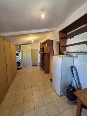 A compact kitchen with a washing machine, a refrigerator, and a vacuum cleaner. - Villa The Sylamston - The Waterfall Experience (Sillans-la-Cascade)