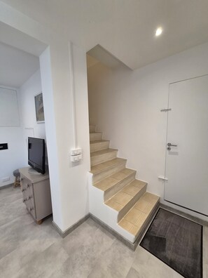 Eine Treppe zu einer Tür, ein Fernseher auf einem Schrank und ein kleiner Hocker.