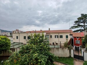 A residential building with a red-tiled roof, a small garden, and a tree in the foreground.