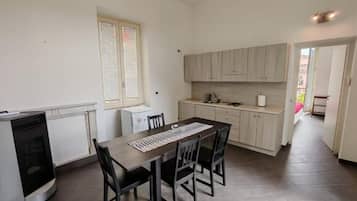 A compact kitchen with a dining table and chairs, a built-in oven, and a window with blinds.
