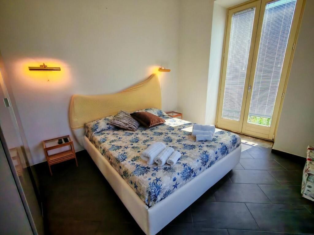Un dormitorio con cama, lámparas de noche, una mesita y una ventana con persianas.