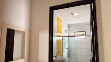 Un pasillo estrecho que conduce a un baño con lavamanos, inodoro y ducha.