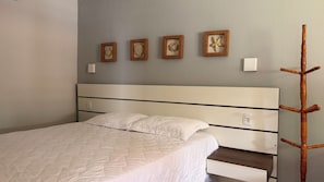 A bed with a white quilted bedspread, a wooden headboard, and a nightstand with a drawer.