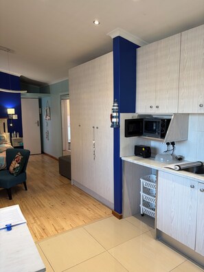 A modern kitchen with wooden cabinets, a microwave, and a toaster. - 32 On Pringle (Cape Town)