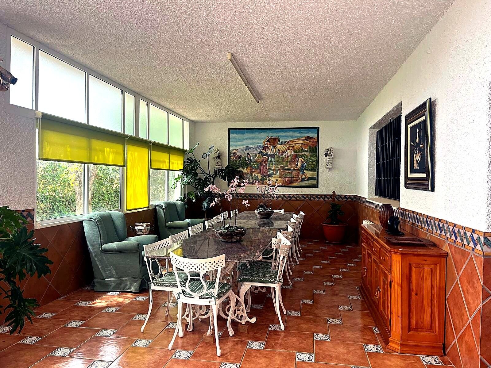 Un comedor con una mesa larga, sillas y un sofá verde.