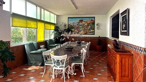 Un espace repas avec une longue table, des chaises et un canapé vert.
