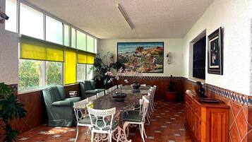 Un comedor con una mesa larga, sillas y un sofá verde.