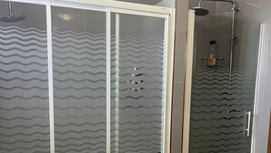 Une salle de bain avec une douche à parois de verre, des toilettes et un carrelage au sol.