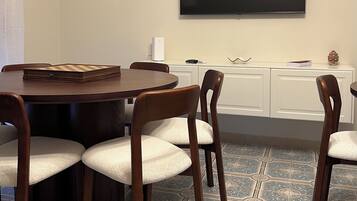 A conference room with a round table, four chairs, a flat-screen TV mounted on the wall, and a patterned floor.
