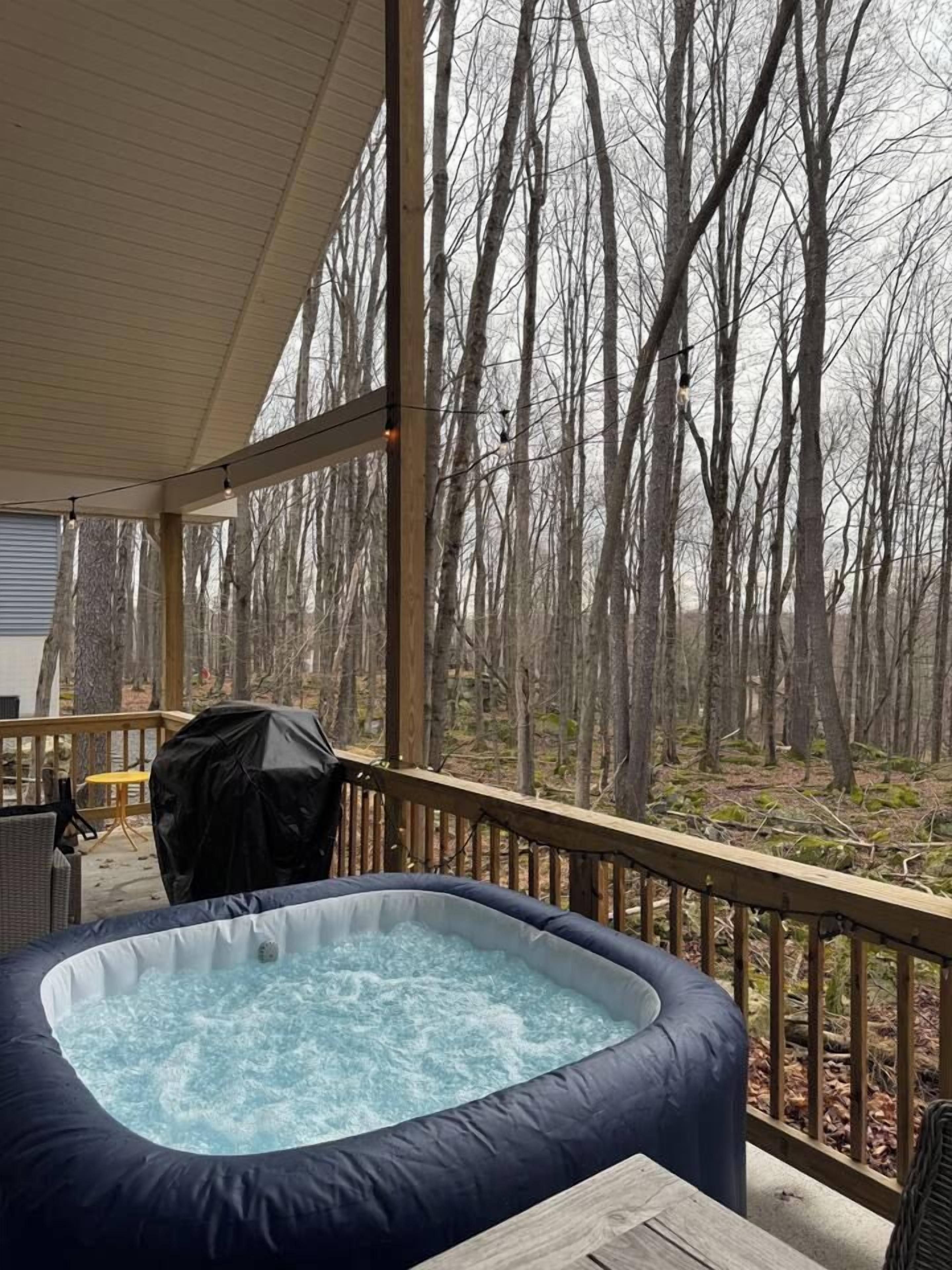 Un bain à remous sur une terrasse en bois, avec vue sur une forêt.