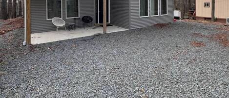 A modern house with a covered porch, large windows, and a gravel driveway.