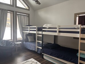Habitació amb literes, finestra, una cadira i taula petita.