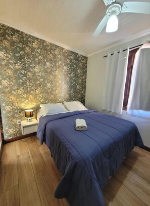 Ein Schlafzimmer mit Bett, Nachttisch, Lampe und Deckenventilator.