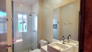 A modern bathroom with a glass shower enclosure, a toilet, and a vanity with a large mirror. - Pousada Casa Hospedaria (Paraty)
