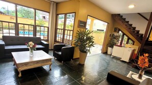 A spacious living area with a sofa, a coffee table, and a potted plant. - Pousada Casa Hospedaria (Paraty)