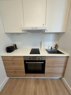 Cozinha compacta com forno embutido, pia e bancada.