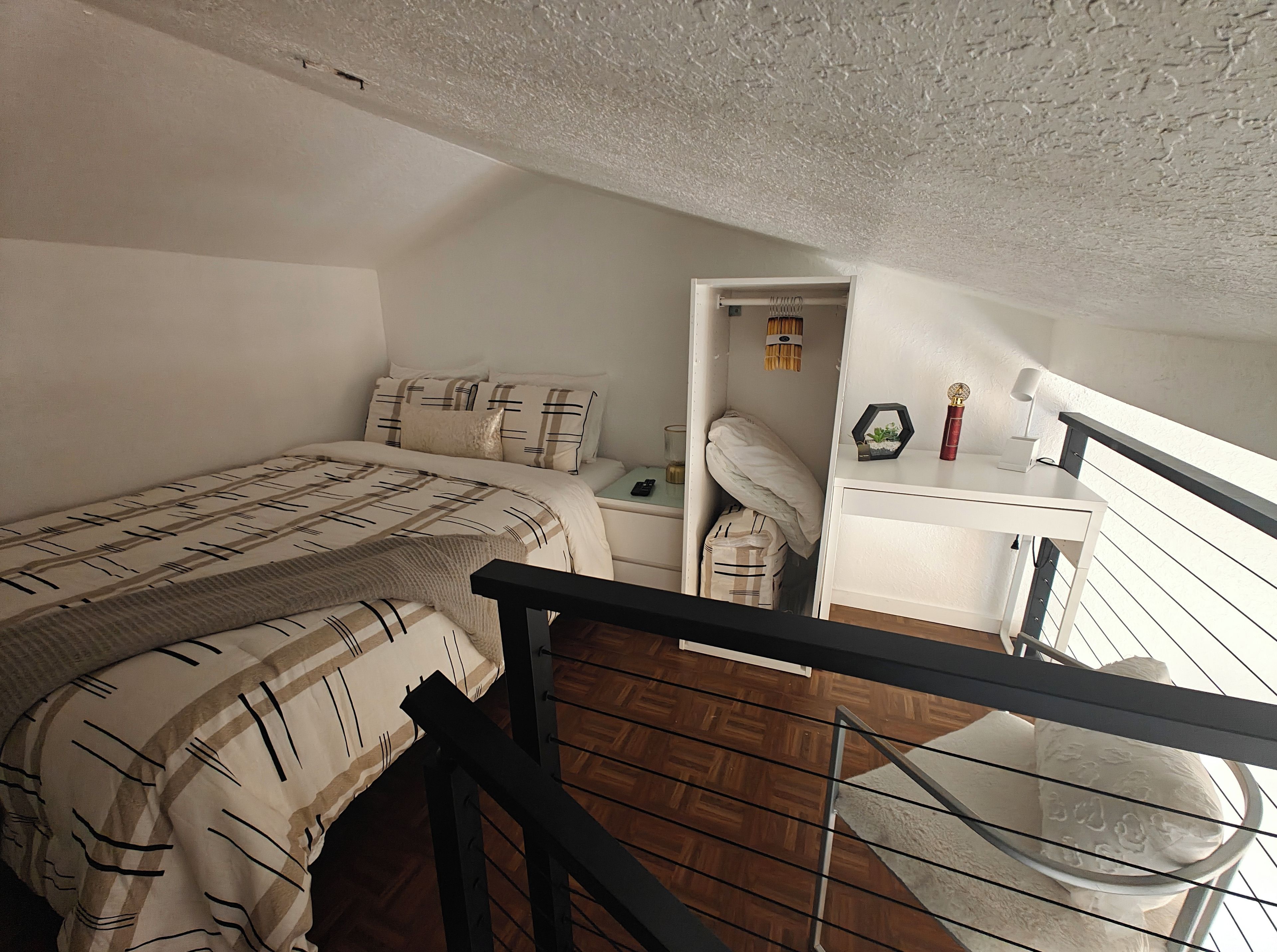 Ein Schlafzimmer mit einem Bett, einem Nachttisch, einem Schreibtisch und einem Fenster.
