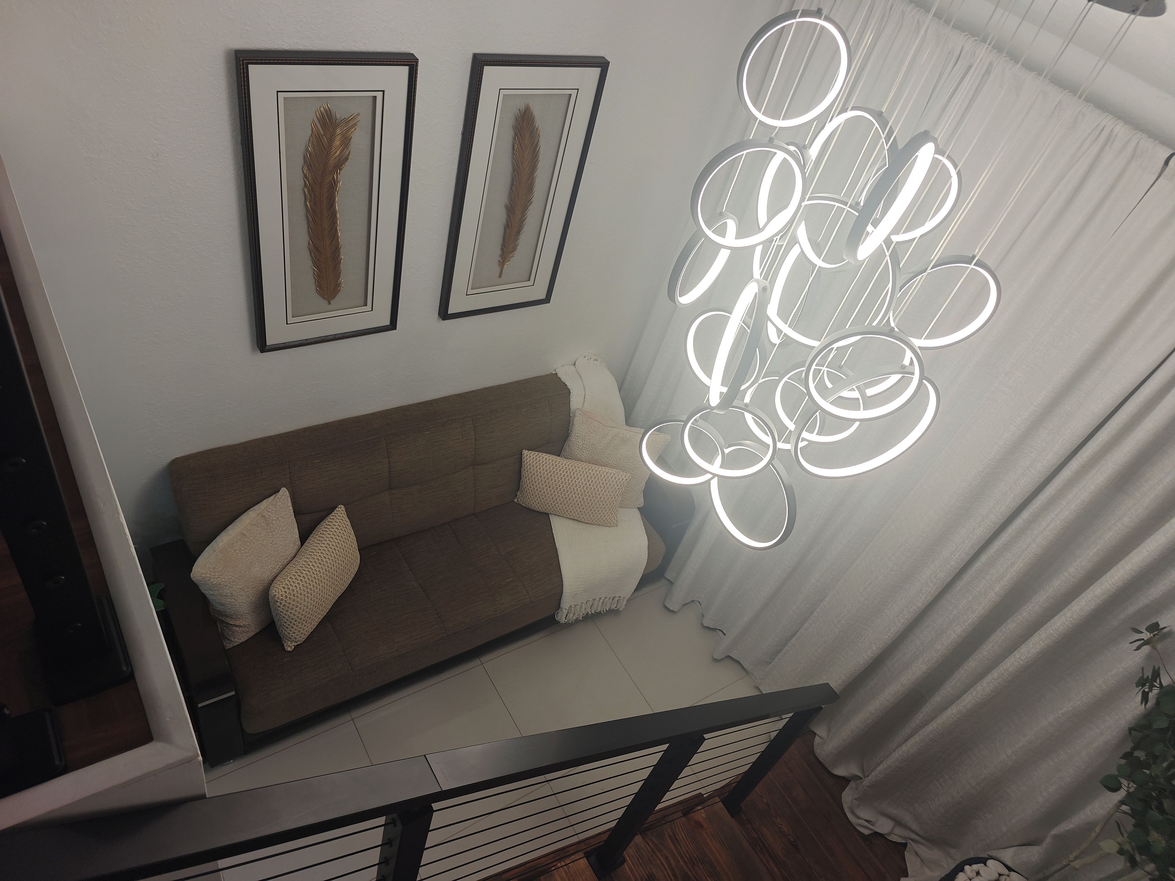 Una sala de estar moderna con un sofá marrón, dos obras de arte enmarcadas y una lámpara de techo circular original.