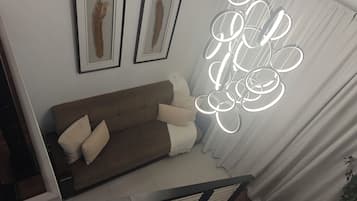 Una sala de estar moderna con un sofá marrón, dos obras de arte enmarcadas y una lámpara de techo circular original.