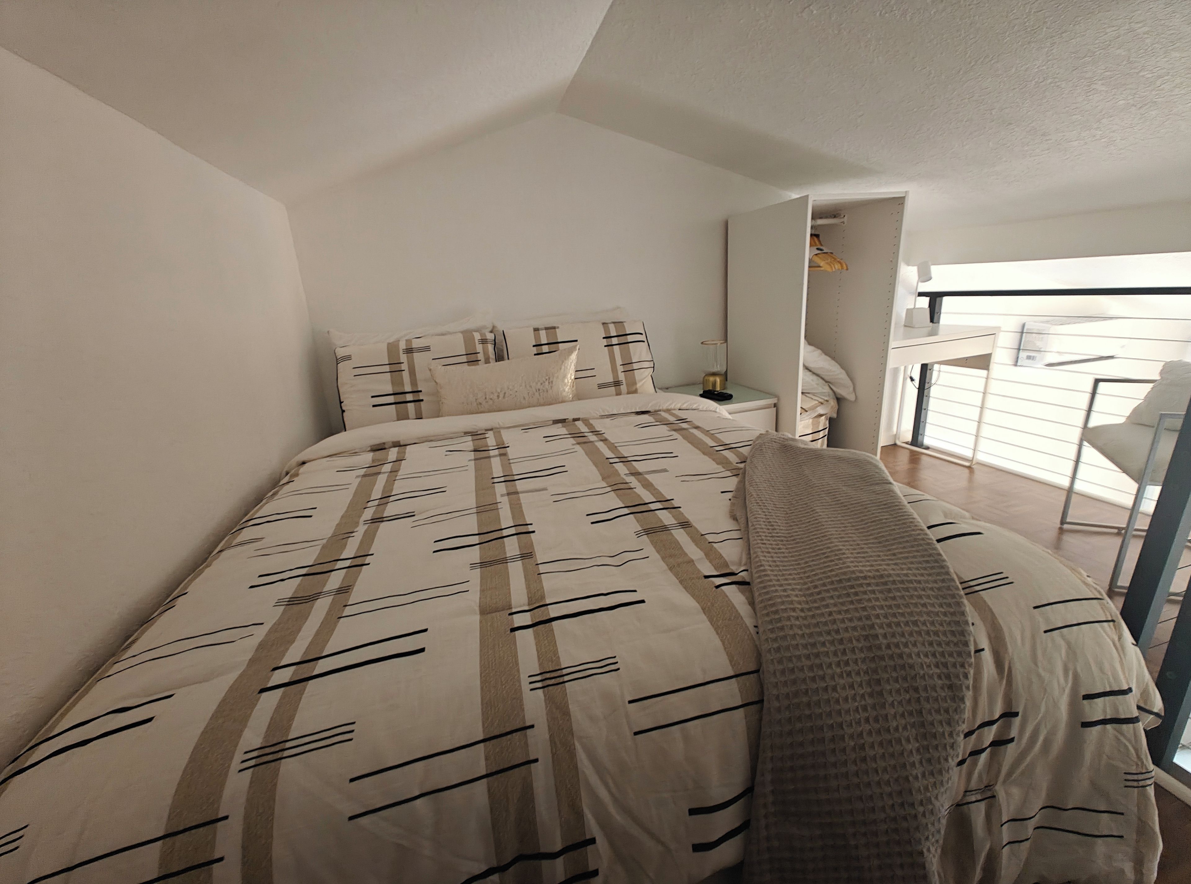 A bedroom with a bed, a nightstand, a chair, and a view of the balcony.
