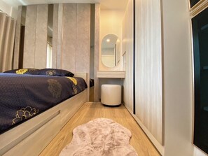 A bedroom with a bed, a bedside table, a mirror, a wardrobe, and a rug. - 2BR Penthouse @ Phyll Phuket next to Central Mall (Tambon Wichit)
