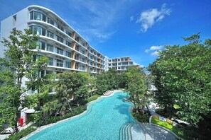 A hotel with a swimming pool surrounded by lush greenery and a clear blue sky. - 2BR Penthouse @ Phyll Phuket next to Central Mall (Tambon Wichit)