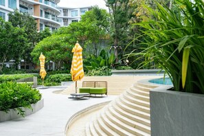 Eine angelegte Außenanlage mit Pool, terrassenförmigen Sitzgelegenheiten und Gartenmöbeln.