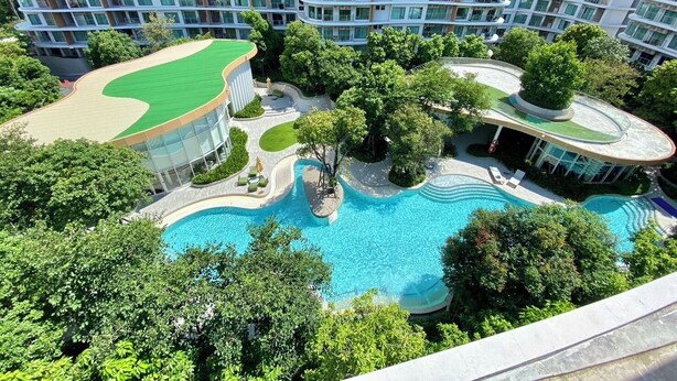 Ein mehrstöckiges Hotel mit Pool und üppiger Bepflanzung.