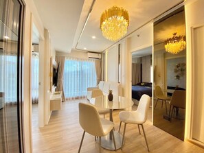 A modern hotel room with a dining area, a bed, and a large mirror. - 2BR Penthouse @ Phyll Phuket next to Central Mall (Tambon Wichit)