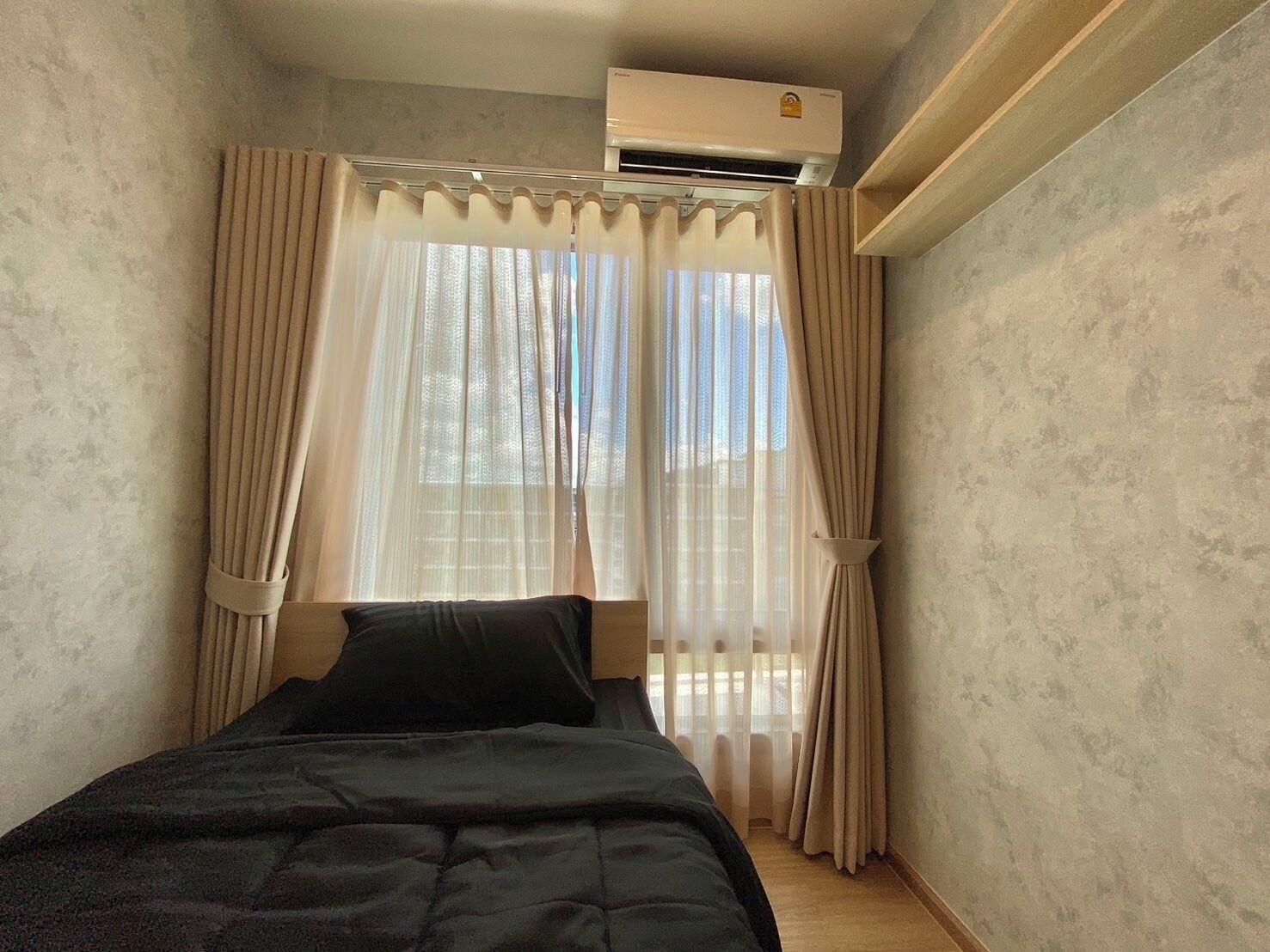 A bedroom with a bed, curtains, and an air conditioning unit.