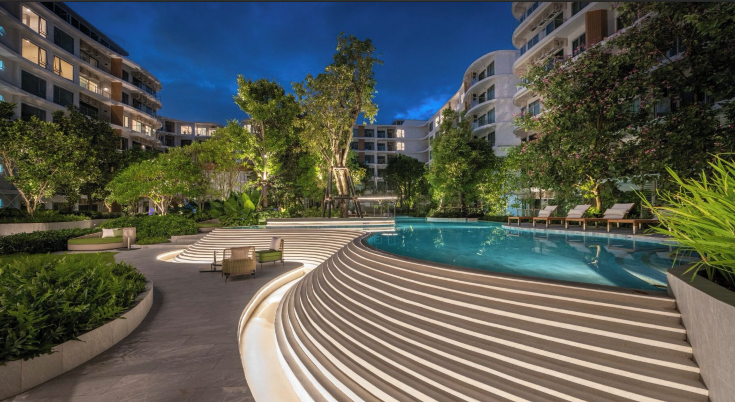 Un hôtel moderne doté d’une piscine, d’un espace extérieur aménagé et d’une végétation luxuriante.