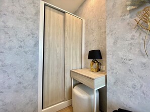 Ein Zimmer mit einer Schiebetür, einem Nachttisch mit Lampe und einem Wandbild.