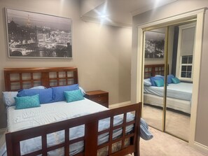 Une chambre à coucher avec un lit, des tables de chevet, un miroir et un tableau représentant un paysage urbain.