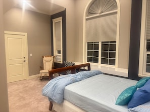 Une chambre à coucher avec un lit, une chaise et une fenêtre.
