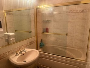 Une salle de bain équipée d’un lavabo, d’un miroir et d’une douche à l’italienne avec une porte en verre.