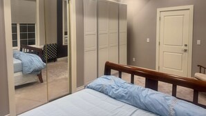 A bedroom with a bed, a wardrobe, a mirror, and a door. - Cozy 1-bedroom private and secured with AC with an independent full bath (Surrey)