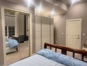 Une chambre à coucher avec un lit, une armoire, un miroir et une porte.