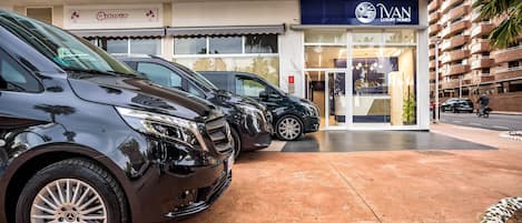 A row of parked cars in front of a building with a storefront labeled 'IVAN LUXURY HOMES.'