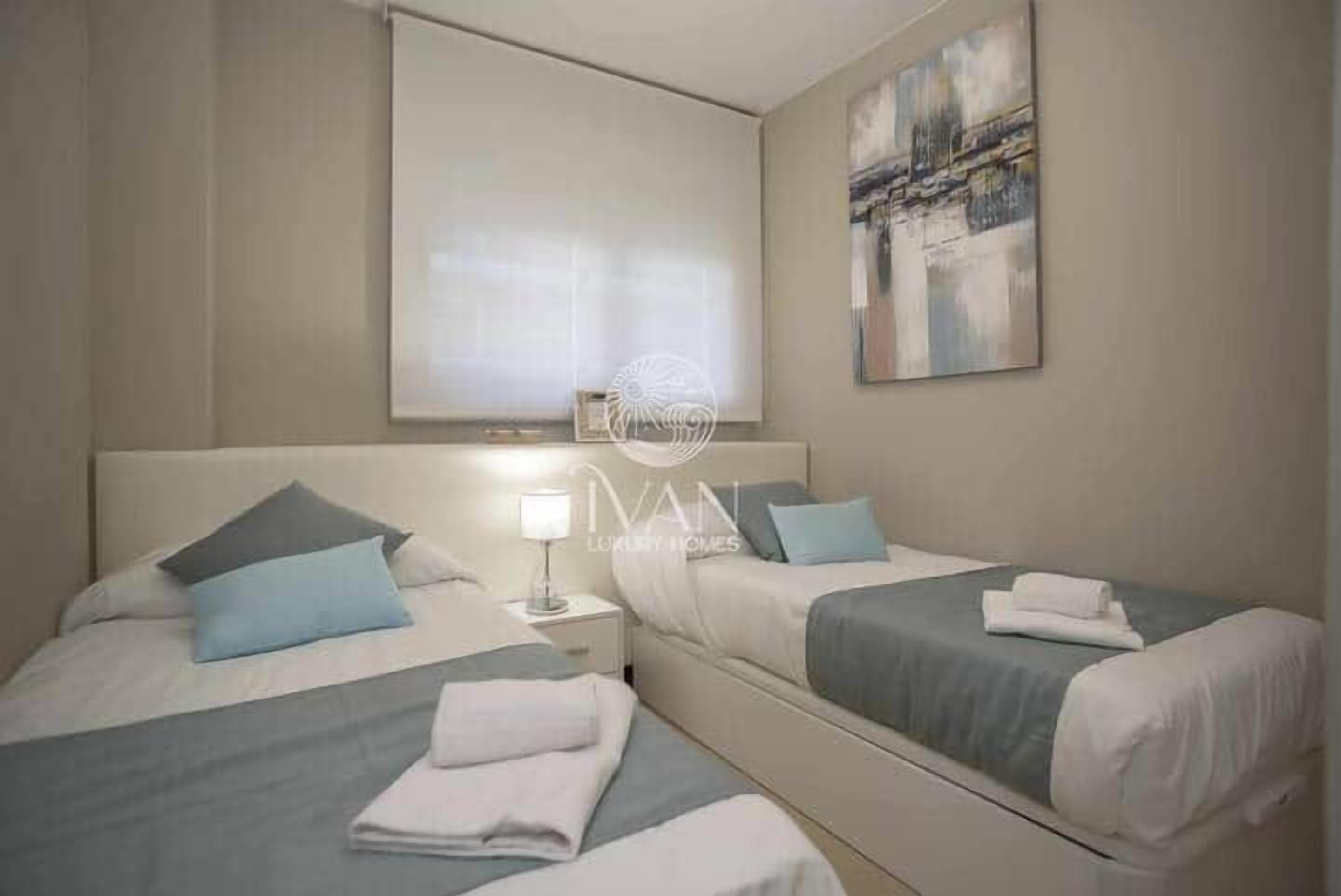 A hotel room with two beds, a nightstand, a lamp, and a painting on the wall.