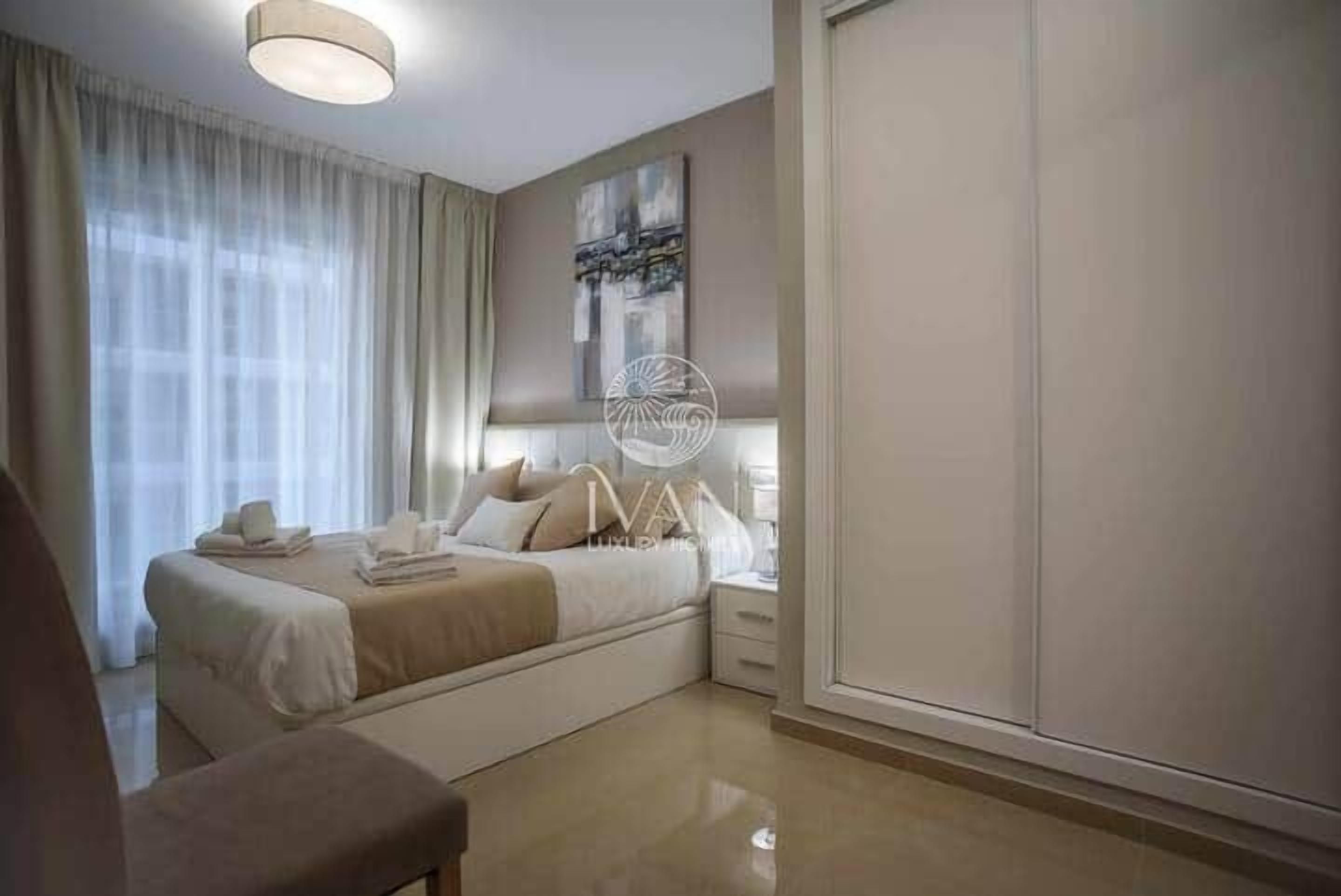 Een moderne hotelkamer met een bed, nachtkastje en een groot raam.
