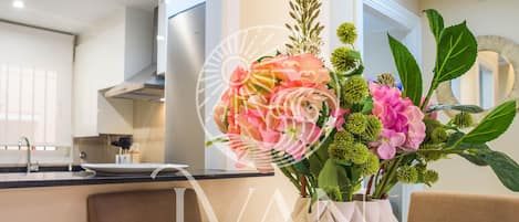 A dining table set with plates, bowls, cutlery, and a vase with flowers.