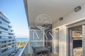 A balcony with a view of the sea, a table and chairs, and a logo for Ivan Luxury Homes. - Cathy Ivan Luxury Homes, 5th Floor North, 1st Line (Oropesa del Mar)
