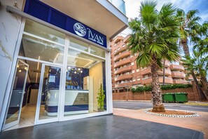 A luxury home store with a modern facade, large glass windows, and a palm tree in the foreground. - Casa Moon Ivan Luxury Homes 1ªPta Sur 1ªLinea (Oropesa del Mar)