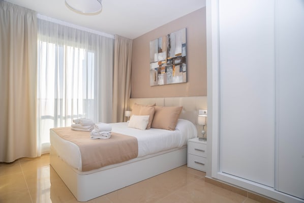 Ein modernes Schlafzimmer mit einem großen Bett, einem Nachttisch, einer Lampe und einem Bild an der Wand.