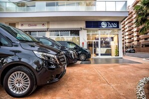 Edifício moderno com fachada de lojas de casas de luxo e um carro estacionado em frente.