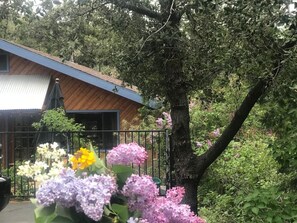 A house with a wooden exterior, a metal roof, and a tree in the background. - Mountain Pines Lodge • Single Level (Wrightwood)